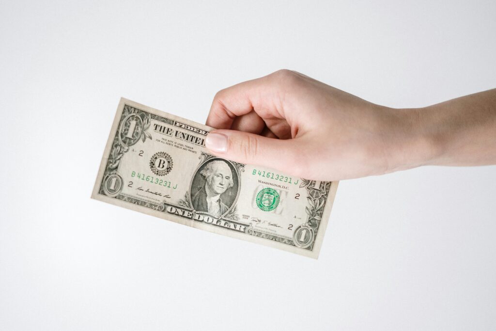 pexels-photo-3943739-3943739 Close-up of a hand holding a one US dollar bill against a white background. Ideal for finance-related themes.